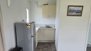 Una cocina compacta con refrigerador, lavamanos y armarios.