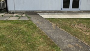 Un edificio de una planta con techo plano, una ventana pequeña y una puerta corrediza de vidrio.
