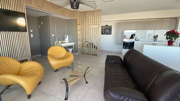 Un salón moderno con un sofá de cuero marrón, dos sillones amarillos y una mesa de centro de vidrio.