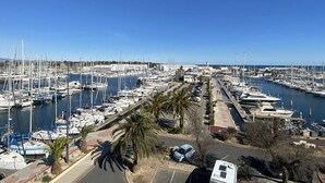Un port de plaisance où sont amarrés de nombreux bateaux, un espace de stationnement et un ciel d’un bleu limpide.