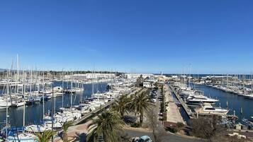Un puerto deportivo con numerosos barcos amarrados, una zona de estacionamiento y un cielo azul despejado.