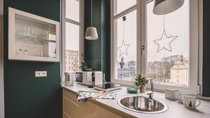 A modern kitchen with a built-in microwave, toaster, and kettle, a window with star decorations, and a view of buildings outside. - Botella Kr Lewskie Studio w Sercu Poznania (Poznań)