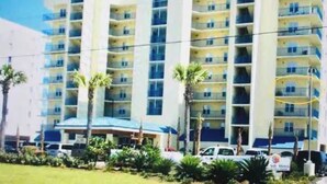A multi-story hotel with balconies, a central entrance, and a parking area. - Newly listed charming  3-bedroom condo with beach view in  Gulf Shores (Gulf Shores)