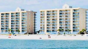 A beachfront hotel with multiple floors, balconies, and a sandy beach in the foreground. - Newly listed charming  3-bedroom condo with beach view in  Gulf Shores (Gulf Shores)
