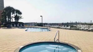 A swimming pool area with a hot tub and lounge chairs. - Newly listed charming  3-bedroom condo with beach view in  Gulf Shores (Gulf Shores)