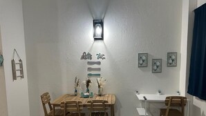 Zona pranzo con tavolo e sedie in legno, parete bianca con lampadario e decorazioni a parete.