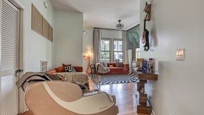 A modern living room with a sofa, a chair, a lamp, and a staircase. - Projector - 5 mins to DT - 4 King Beds - Massage Chair (Savannah)