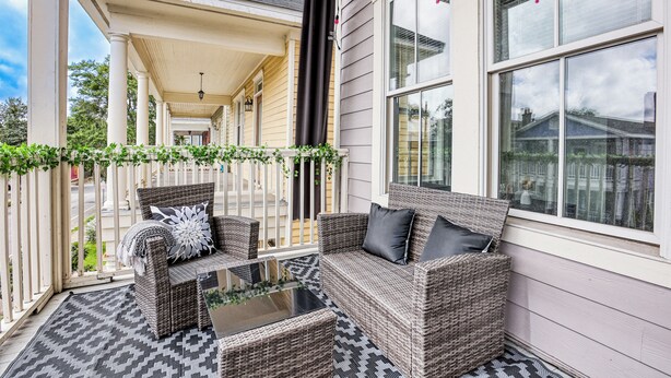 A covered porch with wicker furniture, a glass table, and a view of the street. - Projector - 5 mins to DT - 4 King Beds - Massage Chair (Savannah)