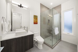 Un bagno moderno con doccia vetrata, lavandino bianco e uno specchio grande.
