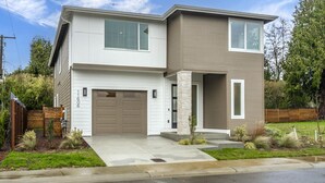 A modern two-story house with a garage, a covered porch, and a landscaped front yard. - Brand New 5BR Home Fenced Yard Ample Parking (Renton)