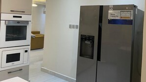 Eine moderne Küche mit Einbauofen, Mikrowelle und einem Edelstahl-Kühlschrank mit Wasserspender.