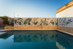 A swimming pool with a decorative wall featuring floral and leaf patterns. - San Lawrenz Farmhouse Rustic Retreat With Pool (San Lawrenz)