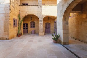 A courtyard with stone arches, potted cacti, and a tiled floor. - San Lawrenz Farmhouse Rustic Retreat With Pool (San Lawrenz)