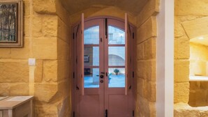 A pink door with glass panels, set in a stone wall with a painting above it. - San Lawrenz Farmhouse Rustic Retreat With Pool (San Lawrenz)