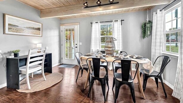 A dining area with a wooden ceiling, a round table, and black chairs. - The Oak Cottage- Charming Downtown Retreat in the Heart of Siloam Springs (Siloam Springs)