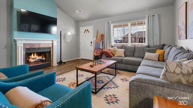 Una sala de estar con chimenea, televisor grande y sofá.