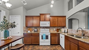 Una cocina moderna con armarios de madera, estufa blanca y encimeras de granito.