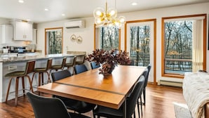 A modern kitchen with white cabinets, a central island, and a dining area with a wooden table and chairs. - Contemporary Northwoods Retreat- In the Heart of Sister Bay (Sister Bay)