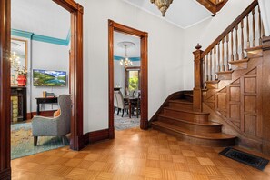 Eine Holztreppe führt zu einer zweiten Etage, einem Essbereich mit Tisch und Stühlen sowie einer Aussicht auf ein Landschaftsbild.