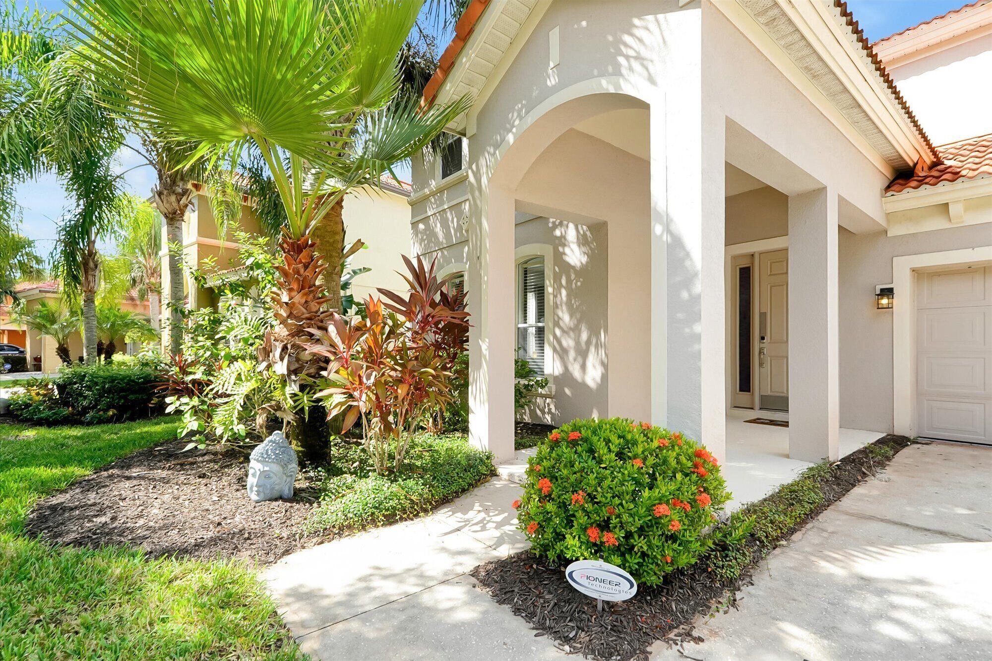 A residential property with a covered porch, a well-maintained garden, and a clear driveway.