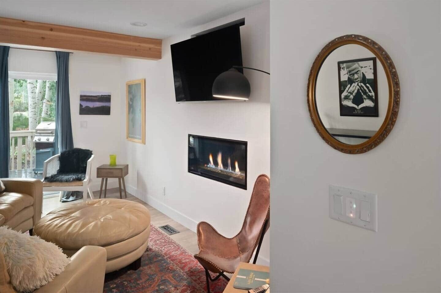 Una sala de estar moderna con chimenea, televisor montado y un cuadro en la pared.
