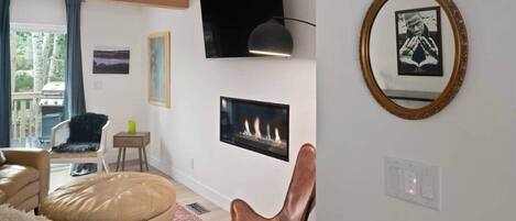 Una sala de estar moderna con chimenea, televisor montado y un cuadro en la pared.