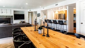 Een moderne keuken met een houten eettafel, barstoelen en een centraal keukeneiland.