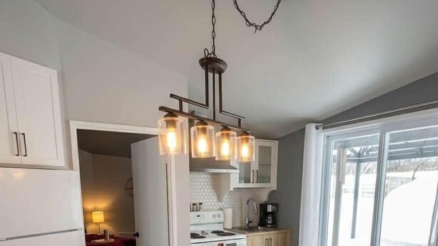 Una cocina moderna con una isla de madera, iluminación colgante y vistas amplias por un gran ventanal.