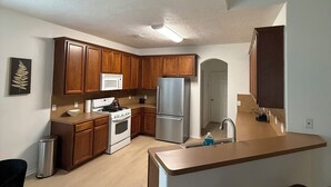 Eine moderne Küche mit Holzausstattung, einem Edelstahlkühlschrank und einem eingebauten Backofen.