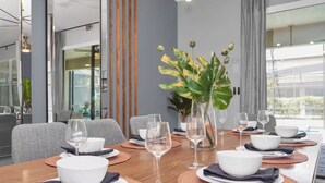 Un comedor con una mesa larga dispuesta para una comida, que incluye tazones, platos y copas de vino.