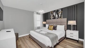 Un dormitorio moderno con una cama grande, mesitas de noche y un elemento decorativo en la pared.