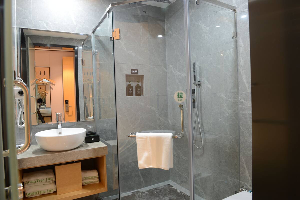 A modern bathroom with a glass-enclosed shower, a white sink, and a mirror above the sink.