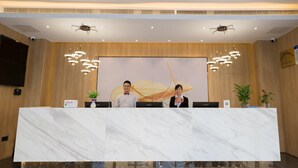 A reception desk with two staff members, a large mural, and modern lighting fixtures. - GreenTree Inn Fuzhou Sanfang Qixiang  (Fuzhou)