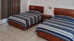 A hotel room with two beds, a ceiling fan, a nightstand, a wall-mounted shelf, and a window with curtains.