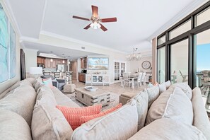 Ein geräumiges Wohnzimmer mit einer großen Couch, einem Essbereich und einer Küche im Hintergrund.