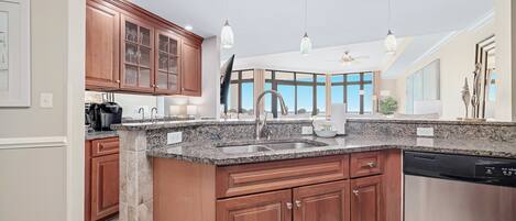 A modern kitchen with granite countertops, wooden cabinets, and a dishwasher.