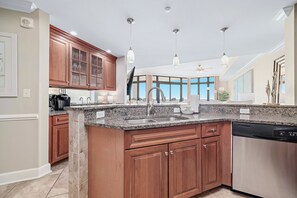 Eine moderne Küche mit Granit Arbeitsplatten, Holzschränken und einem Geschirrspüler.