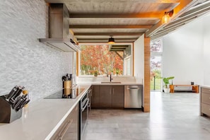 Eine moderne Küche mit großem Fenster, Edelstahlgeräten und minimalistischem Design.
