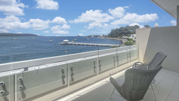 Een balkon met uitzicht op zee, een stoel en een leuning.