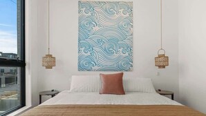 Un dormitorio con una cama grande, dos mesitas de noche, una ventana con vistas y una obra de arte colgada en la pared.