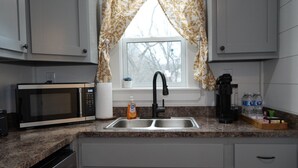 A kitchen with a built-in microwave, a sink, a coffee maker, and a dish soap bottle.