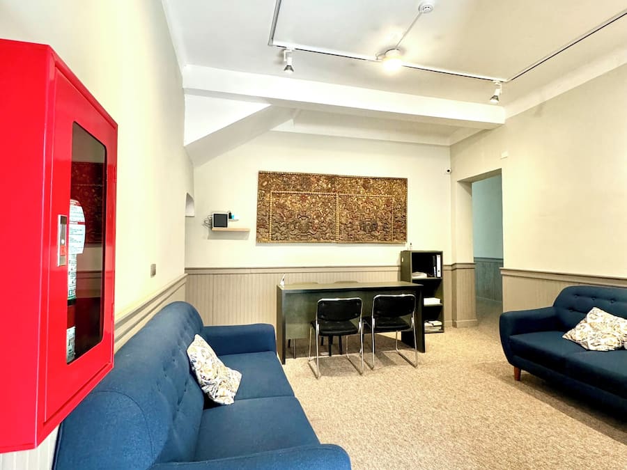 Uma sala de estar moderna com um sofá azul, um armário vermelho e uma área de jantar com uma mesa e cadeiras pretas.