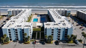 Un hôtel de grande hauteur doté d’une piscine sur le toit, offrant une vue sur la plage et disposant d’un parking.