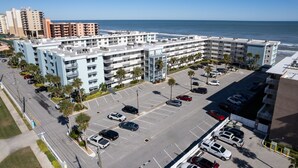 Un hôtel à plusieurs étages doté d’un parking, situé à proximité d’une plage et offrant une vue sur l’océan.