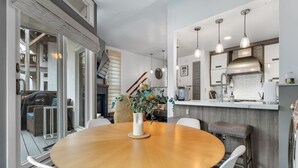 A modern kitchen with a central island, pendant lighting, and a view of the outdoor area. - Bridges Cozy Hideaway at Sugarbush (Warren)