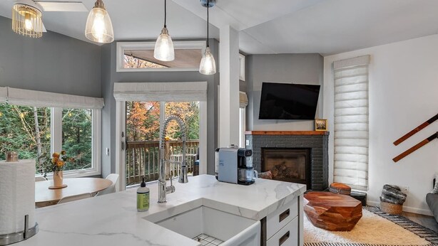 A modern kitchen with a large island, a fireplace, and a TV mounted on the wall. - Bridges Cozy Hideaway at Sugarbush (Warren)