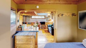A cozy room with a wooden ceiling, a dining area with a table and chairs, a sofa, and a TV. - VT Guest Cottage at Sugarbush in Moretown, VT (Northfield)
