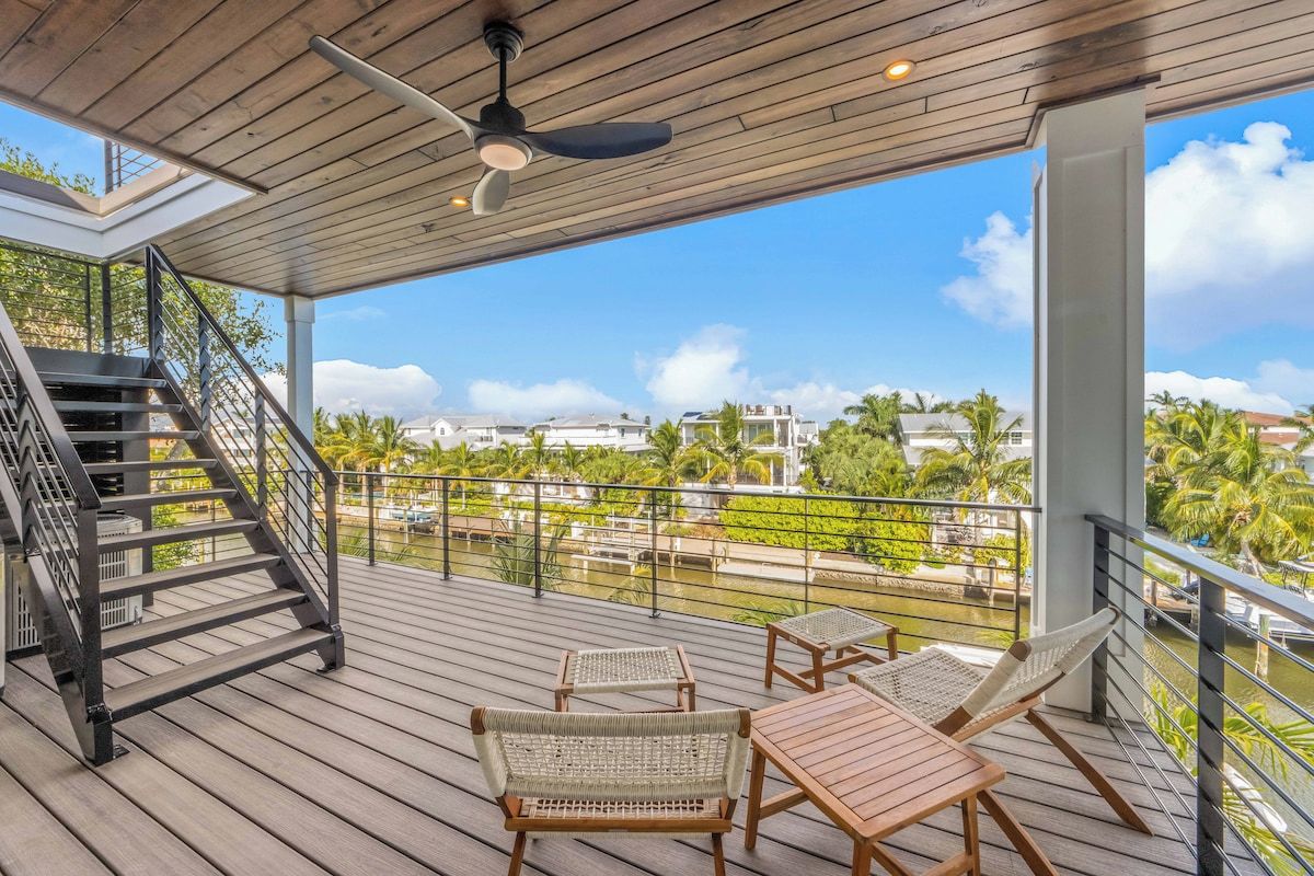 A wooden deck with a staircase, two wicker chairs, and a table.