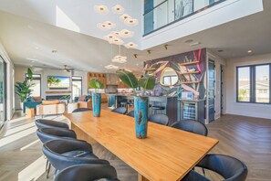 A spacious dining area with a long wooden table, black chairs, and decorative vases. - Bimini Sunrise (Anna Maria)