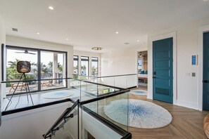 A modern interior with a glass railing, a round rug, and a view of the outdoors. - Bimini Sunrise (Anna Maria)